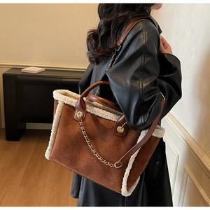 Detail view of brown suede tote bag featuring white faux shearling trim and gold chain detail