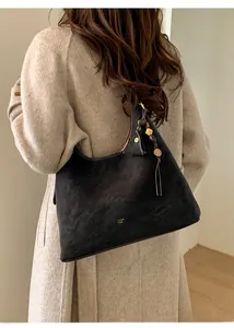 Detail of black matte suede hobo bag with gold logo and wooden bead tassel pendant