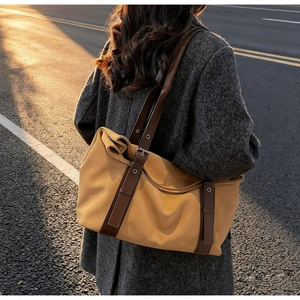 Détail d'un grand sac cabas jaune gingembre avec lanières en cuir marron et boucles en métal
