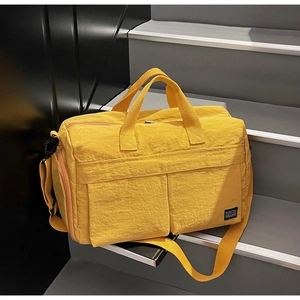 Detail of yellow travel bag with dual pockets and adjustable strap on stairs