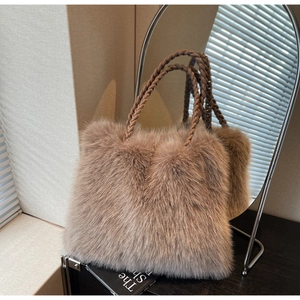 Detail of plush tote bag in faux fox fur with decorative woven handle on a desk