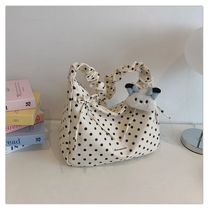 Close-up of pleated polka dot shoulder bag with cute plush puppy charm and ribbon detail