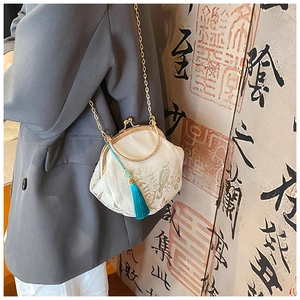 Detail of embroidered silk shell bag with chain strap and turquoise tassel charm