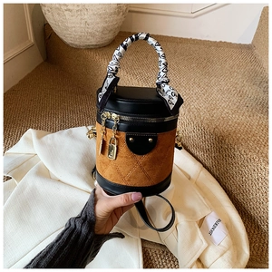 Detail of a quilted suede cylinder bucket bag with a heart-patterned silk scarf on handle