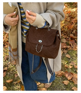 Outdoor shot of dark brown quilted suede backpack with silver twist lock and chain strap