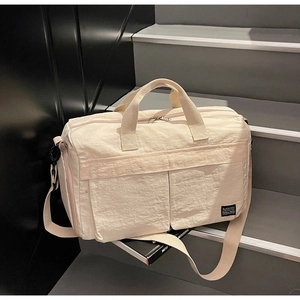 Close-up of beige travel bag with large front pockets and adjustable shoulder strap