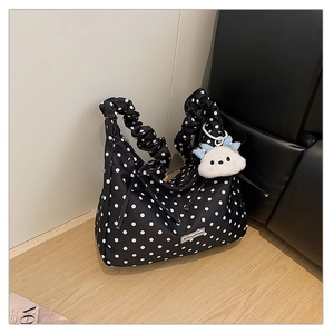 Close-up of black polka dot handbag featuring a scrunchie handle and plush cloud charm