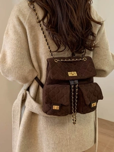 Deep brown quilted suede backpack with gold chain straps worn with a wool coat