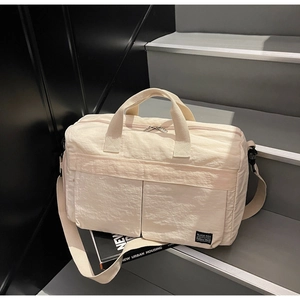 Detail of off-white travel bag with dual handles, shoulder strap and front pockets