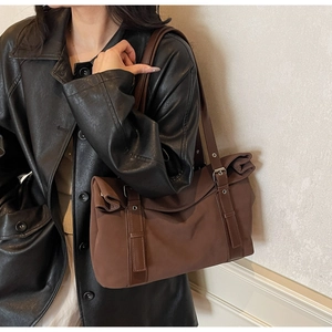 Détail d'un sac porté épaule marron avec sangles en cuir et boucles métalliques
