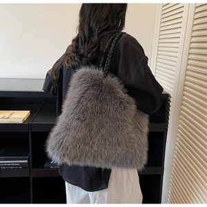 Detail view of grey faux fur tote bag with black woven handles in a minimalist setting