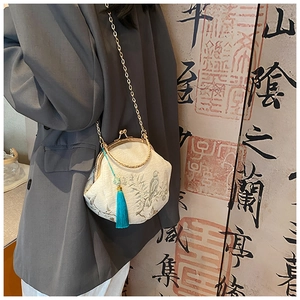 Close-up of embroidered shell bag with bird patterns and blue tassel detail