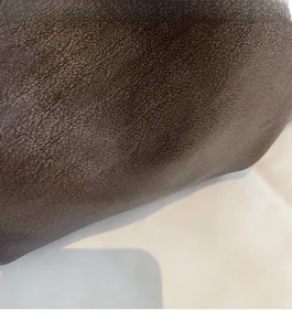 Vue macro détaillée du cuir marron foncé avec logo doré estampé sur la surface du sac