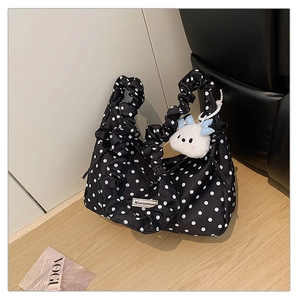 Detailed close-up of a black polka dot bag with ruffled handles and a plush dog charm