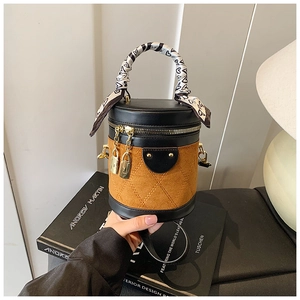 Close-up of quilted cylinder bucket bag with gold locks and heart-pattern scarf handle