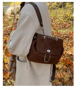 Close-up of mocha brown quilted suede bag with silver turn-lock and metal chain strap
