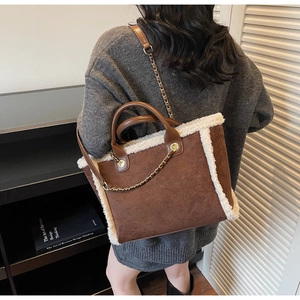 Detail of plush faux shearling trim on brown suede tote bag with golden metal chain strap