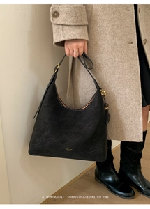 Detail of PANTOR LONDON gold logo on matte black leather minimalist shoulder bucket bag