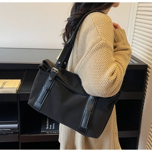 Détail du sac cabas en nylon noir avec des lanières en cuir et boucles métalliques