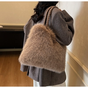 Detail of plush faux fur tote bag featuring woven leather handles on grey coat