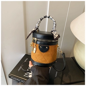 Detail view of brown suede cylinder bag with diamond quilting and silk scarf handle