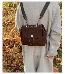 Detail of dark brown suede backpack with quilted diamond pattern and silver twist lock