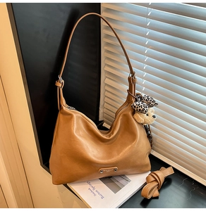 Close-up of a vintage brown hobo bag with teddy bear charm and extra shoulder strap