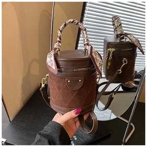 Detail of brown quilted cylinder bag with heart scarf handle and dual metal zippers