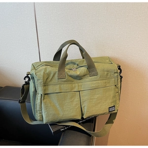 Close-up of olive green waterproof nylon travel bag with multi-pocket storage and straps