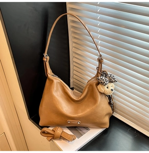 Brown leather hobo bag with adjustable strap and cute leopard bow dog charm detail