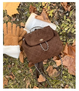 Close-up of brown suede quilted backpack with gold turn-lock and chain strap detail