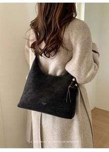 Detail view of large black retro matte shoulder bag with wooden bead and leather tassels
