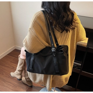 Vue de dos d'un grand sac cabas noir porté à l'épaule dans un décor intérieur chaleureux