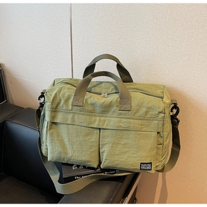 Detail view of large green travel bag with front zip pockets and durable nylon texture