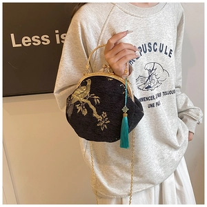 Detail of elegant black shell bag with golden embroidery and vintage tassel decoration
