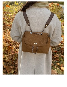 Close-up of brown suede quilted backpack with chain drawstring and metal twist lock detail