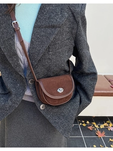 Detail of dark brown suede saddle bag with silver rotary lock for winter fashion