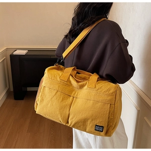 Detail of yellow large travel bag with adjustable shoulder strap and multi-pocket design