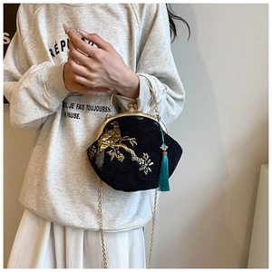 Detail of vintage kiss-lock bag with bird embroidery, metal handle, and silk tassel