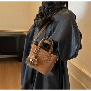 Detail of brown vintage mini tote bag with logo print and cute brown plush eye charm