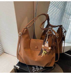 Détail du sac cabas marron en similicuir avec charm d'ours et étoile sous une lumière douce