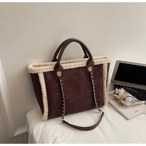 Close-up of brown suede tote bag with cream shearling trim and golden metal chain strap
