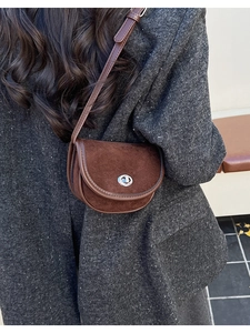 Detail view of a vintage dark brown suede saddle bag with a silver rotating clasp