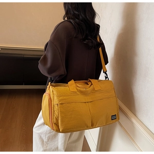 Close-up of a yellow large capacity travel bag with multiple pockets and shoulder strap