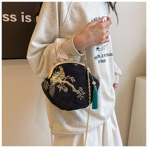 Detail of embroidered floral shell bag with golden chain strap and silk tassel charm