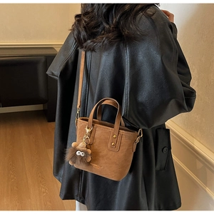 Detailed back view of a brown stylish bucket bag with a cute plush monster charm