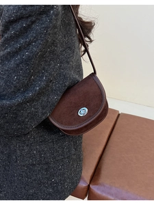 Detail of vintage brown suede saddle bag with silver ring lock on tweed coat texture