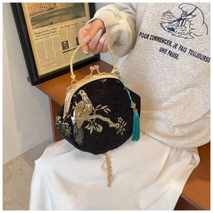 Detail of vintage black shell bag featuring golden bird embroidery and silk tassels