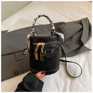 Detail of black bucket bag featuring diamond stitching, silk scarf handle, and gold hardware