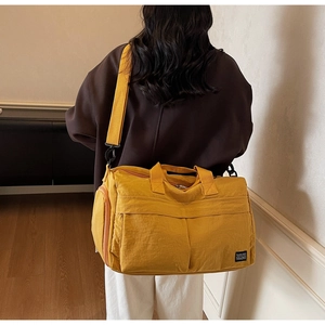 Detail of a ginger yellow travel bag with large front pockets and adjustable shoulder strap